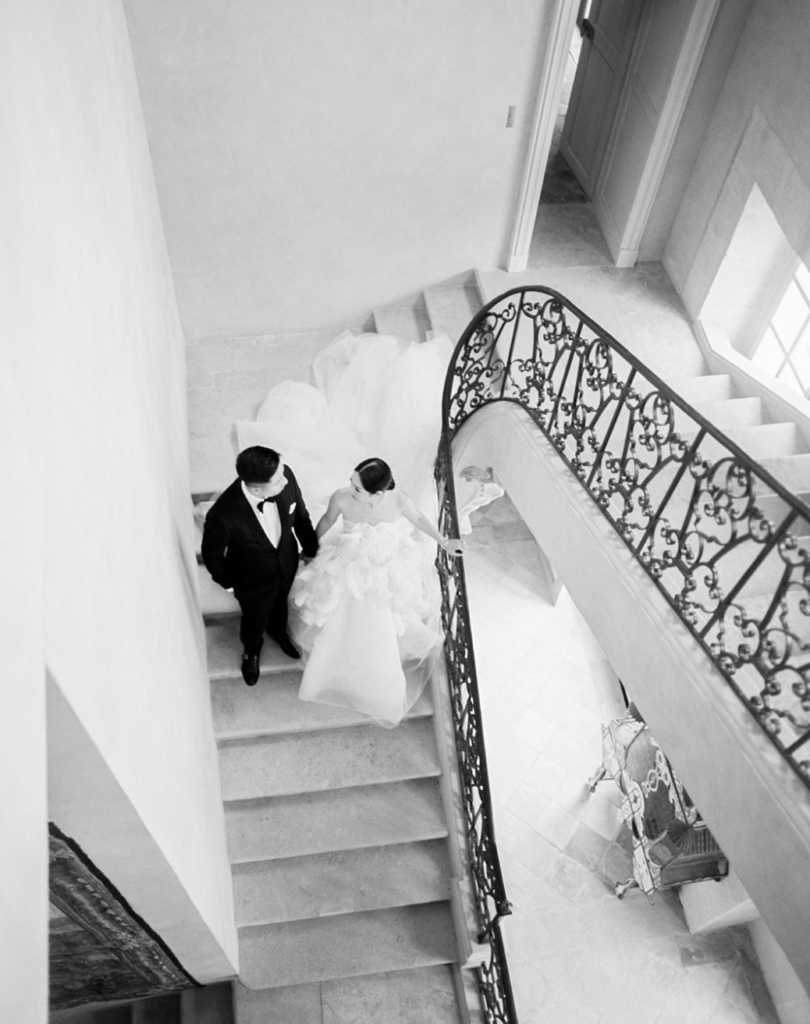 Destination wedding planner Chateau De Villette bride and groom walking down indoor staircase in black and white
