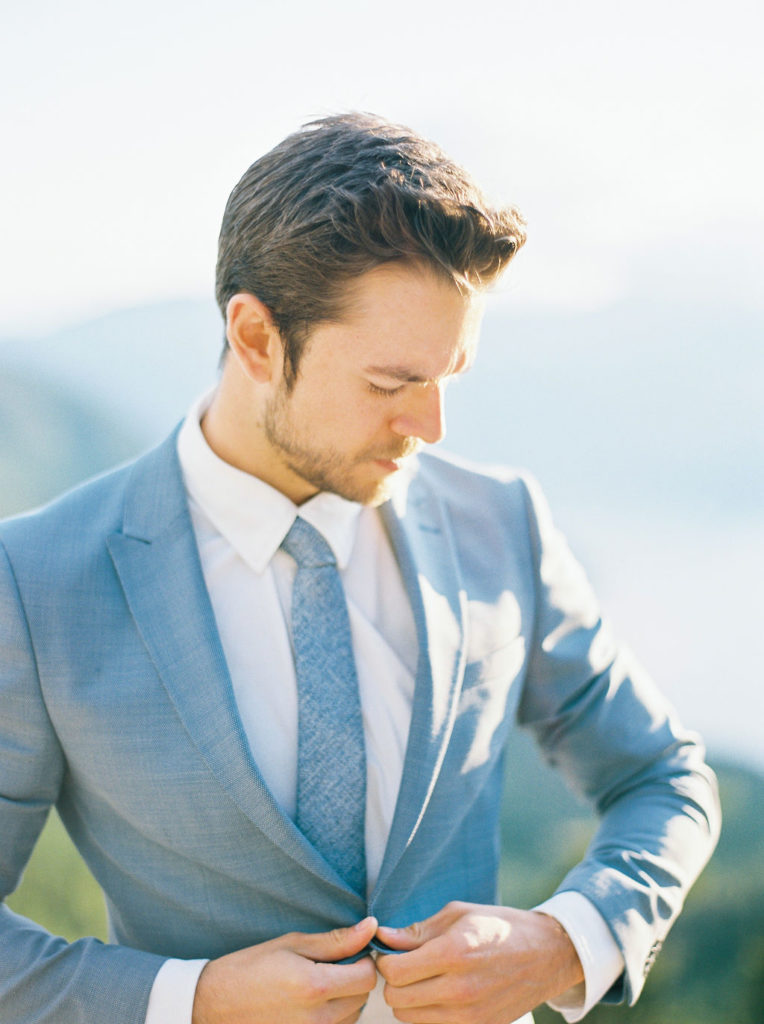 Groom buttoning his light blue suit