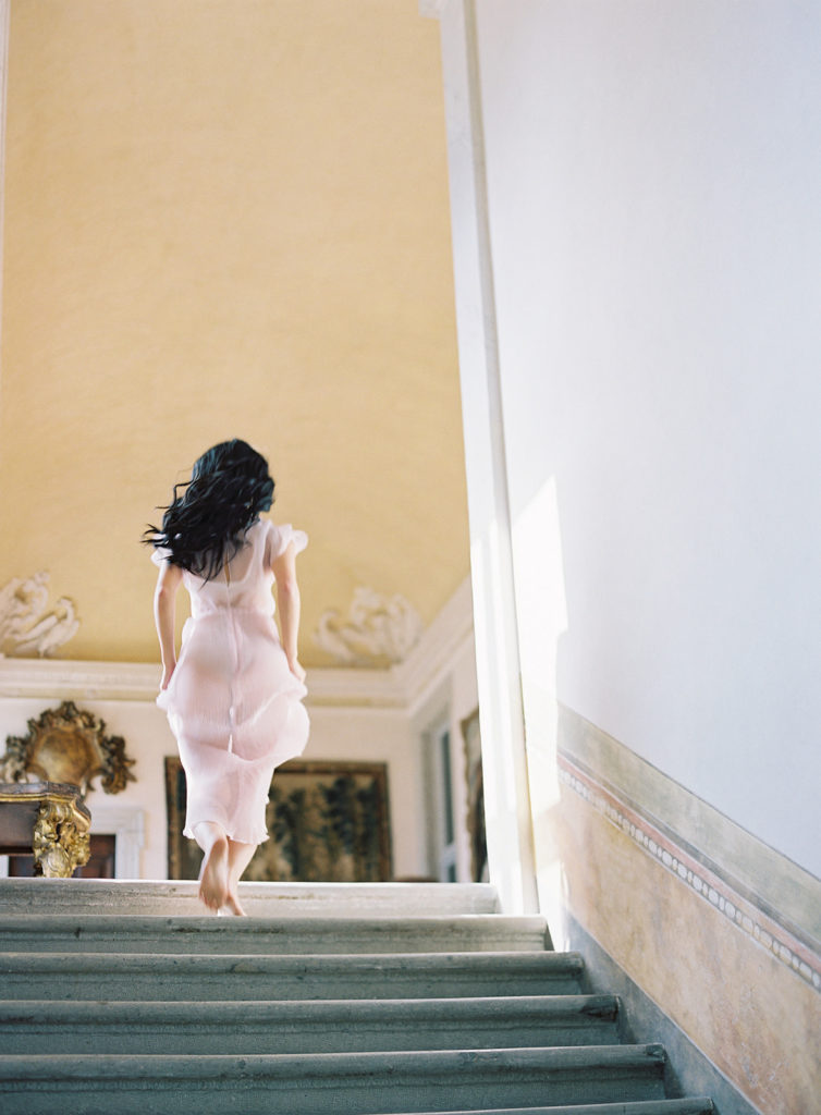Bride running up stairs in villa