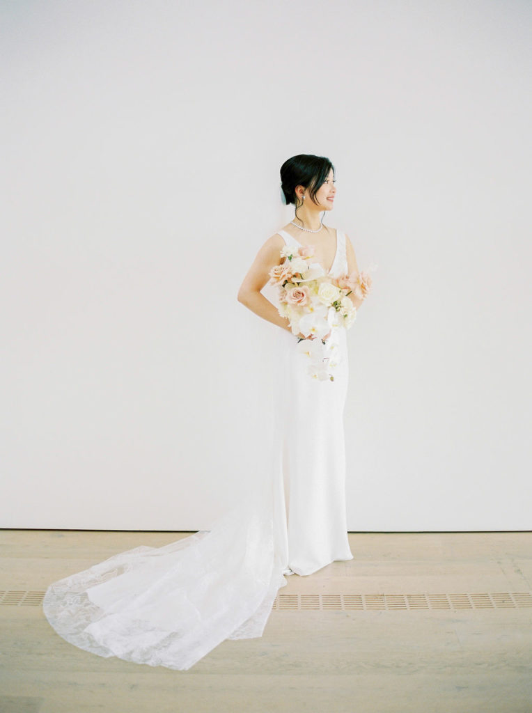 Bride in minimalistic dress holding bouquet