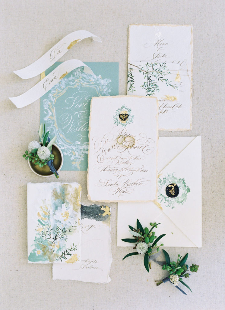 Flatlay of green and gold wedding invitation suite