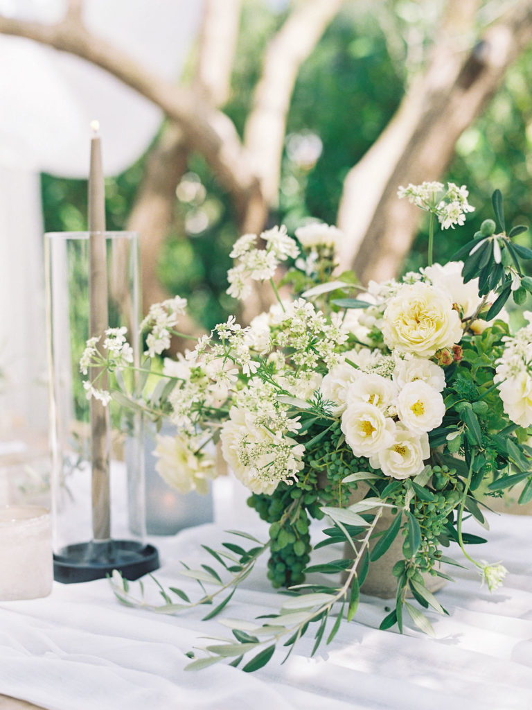 Green and white floral centerpiece beside candles