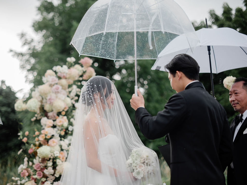 groom holding umbrella for bride