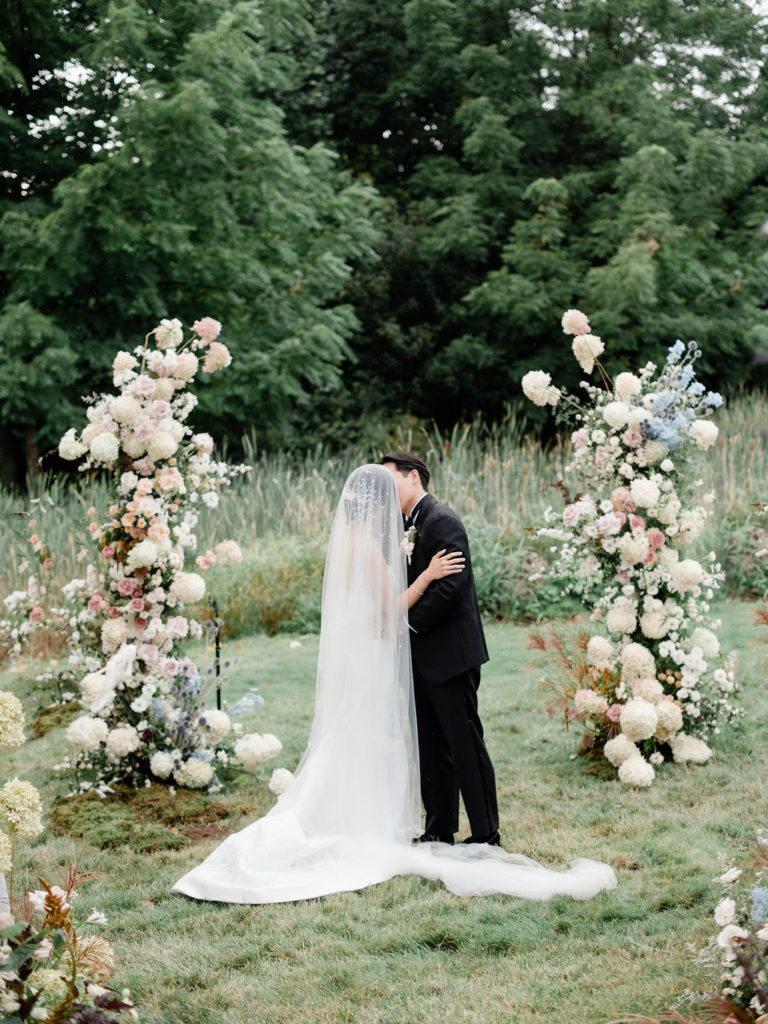 newlyweds kiss at floral arch