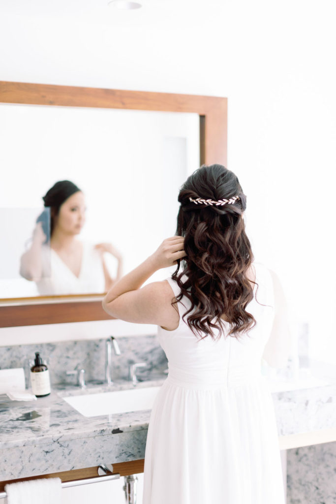 bride fixing hair in bathroom