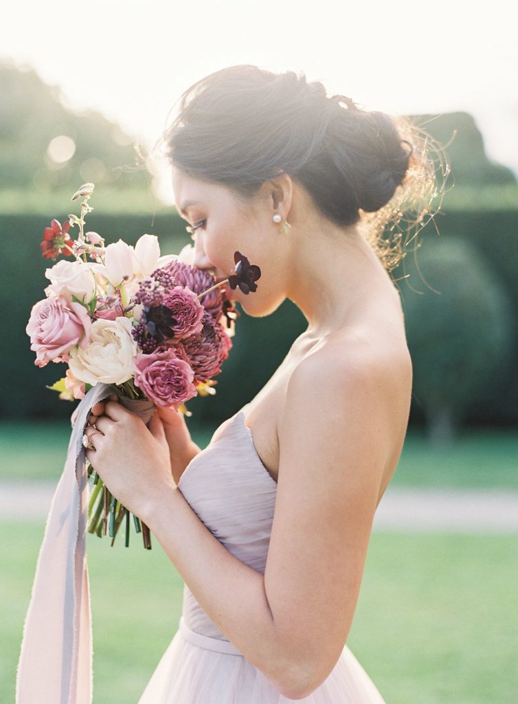 Bride smelling bouquet at sunset