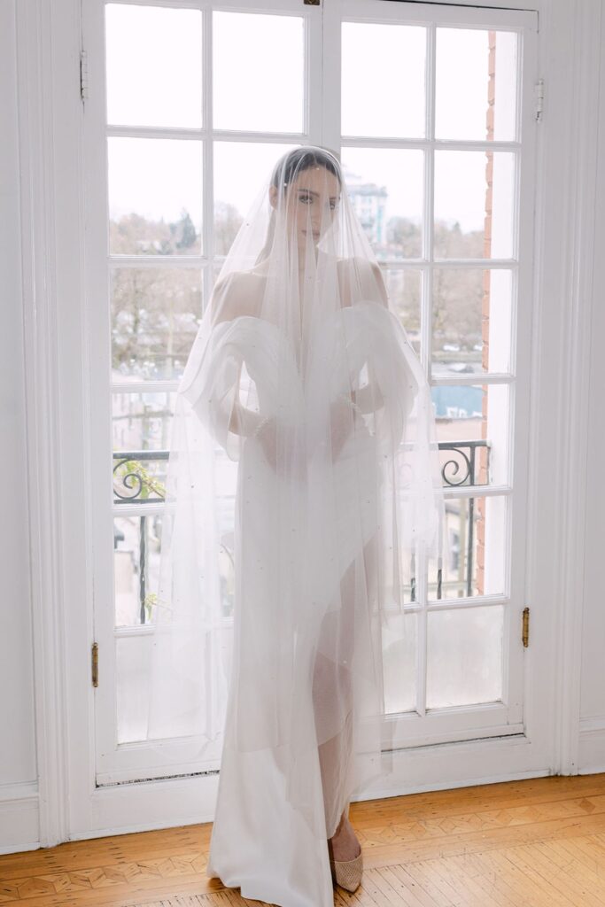 bride posing in veil in front of French doors