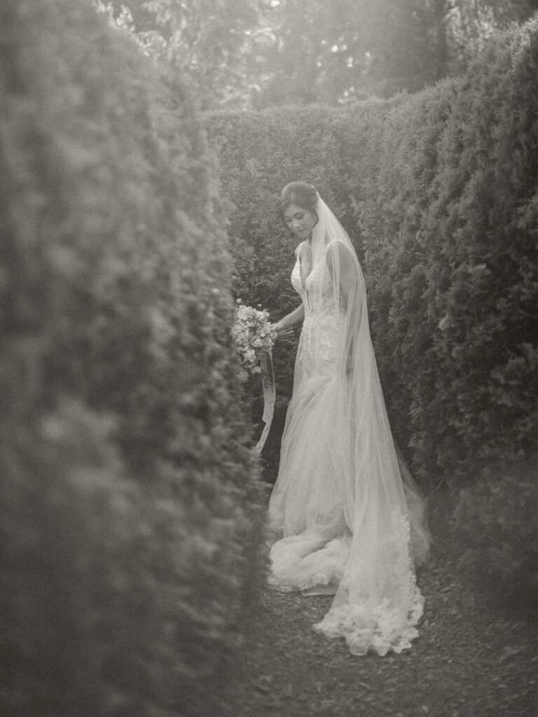 black and white of bride in wedding gown in maze