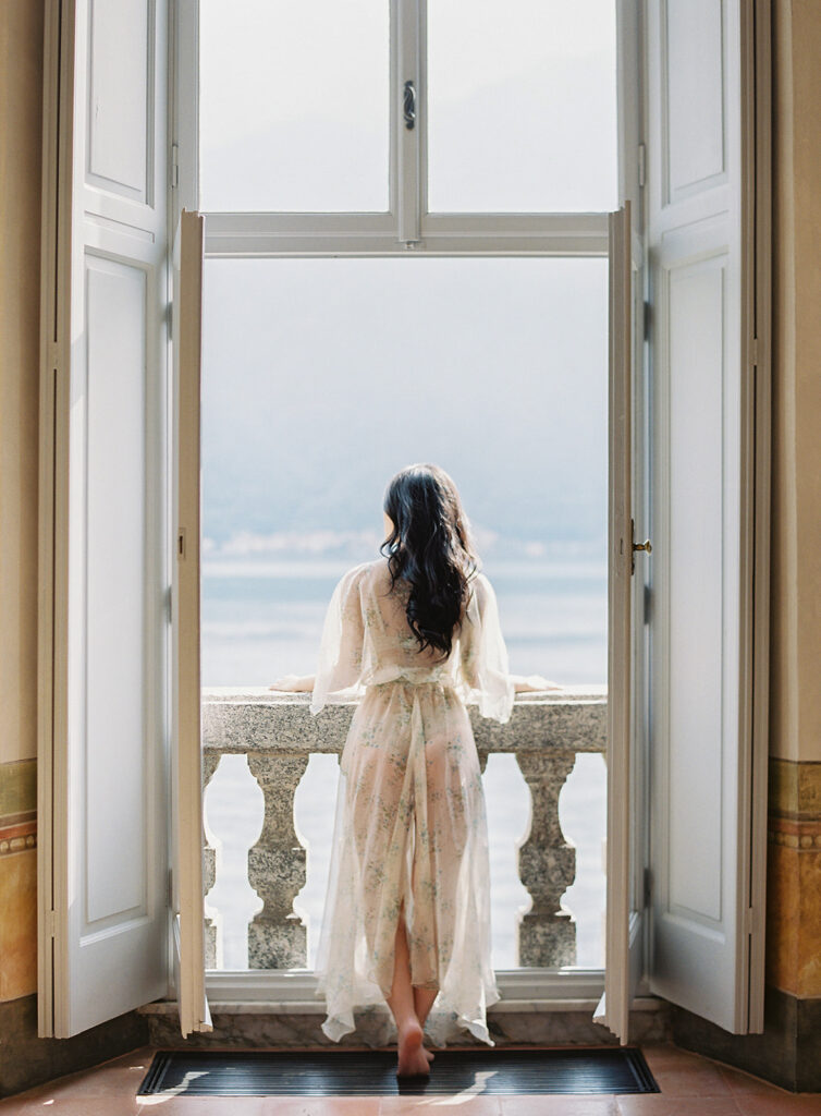 Bride looking out of window at Lake Como