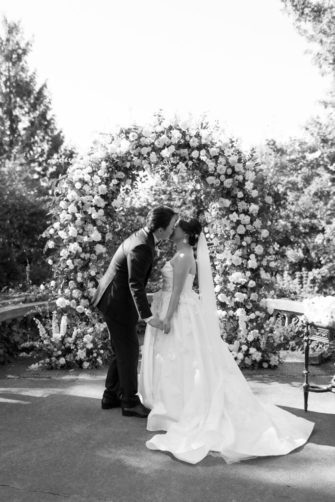 newlyweds kiss under arch on juliet balcony