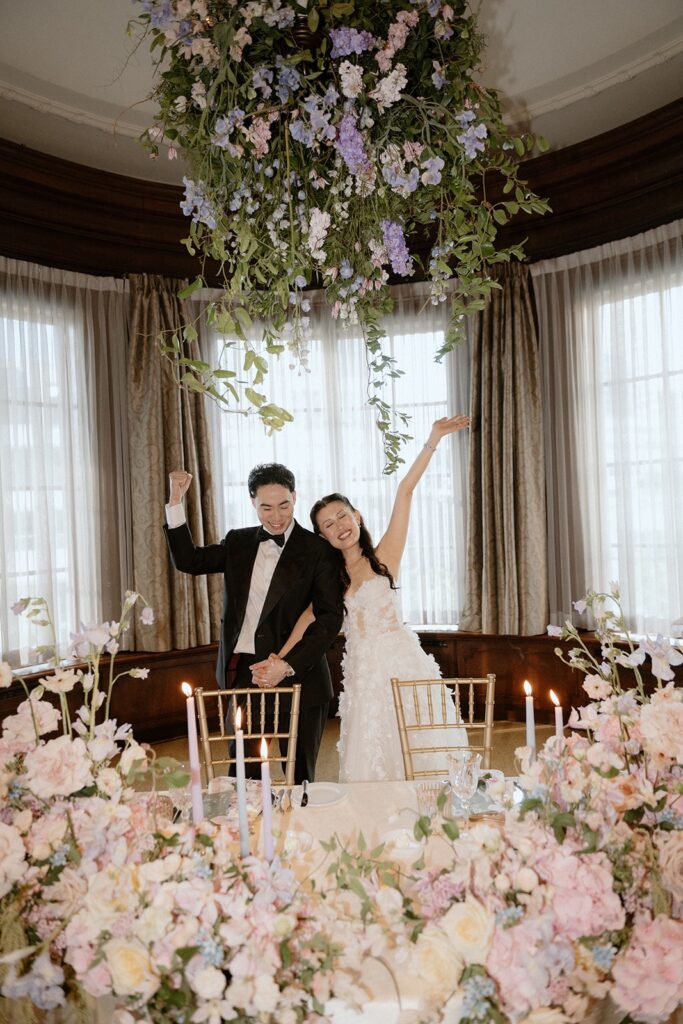 bride and groom happy under floral chandelier